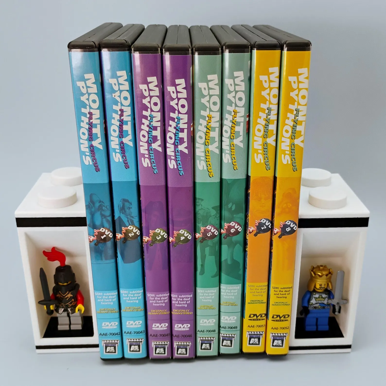 LEGO® minifigure bookends holding colorful books and DVDs with integrated display mounts for collectible figures.